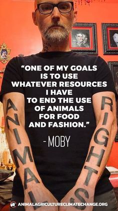 a man with tattoos on his arms is standing in front of an orange wall and has a quote from moby