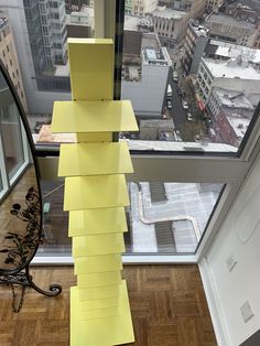 a stack of yellow post it notes sitting on top of a wooden floor next to a window