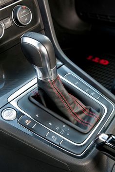 an automatic gear lever in a car with red stitchs on the dash and center console