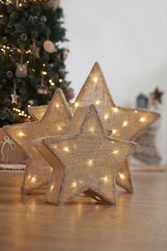 two star shaped lights sitting on top of a wooden table next to a christmas tree