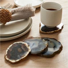 three agate coasters sitting on top of a wooden table next to a cup of coffee