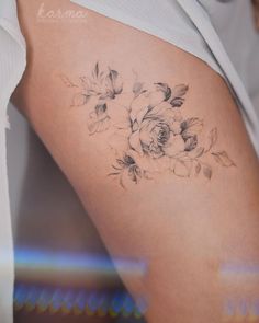 a close up of a woman's thigh with flowers tattooed on the side and behind her