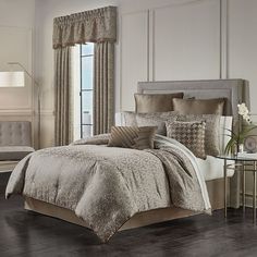 a bedroom with white walls and flooring has a large bed covered in beige linens