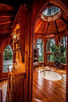 the inside of a wooden cabin with wood floors and arched doorways leading to an outdoor hot tub