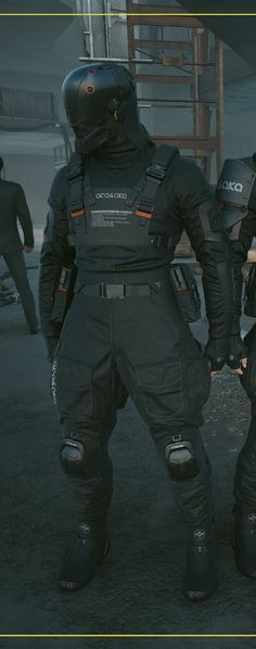 two people in black suits standing next to each other with helmets and body armor on