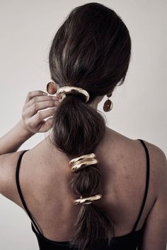 a woman with her hair in a high ponytail and gold rings on the back of her head