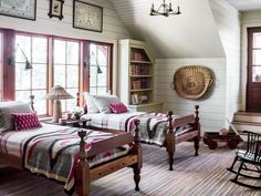 two beds in a room with windows and rugs on the floor next to each other