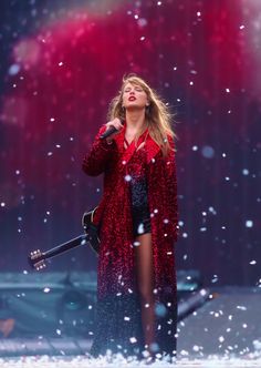 the singer is singing on stage with snow falling all around her and holding an electric guitar