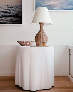 a table with a lamp, bowl and pictures on the wall