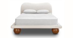 a white bed with two pillows on top of it and a wooden foot board in the middle