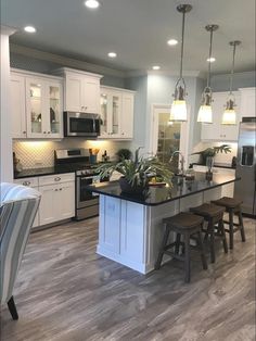 a large kitchen with white cabinets and black counter tops, an island in the middle