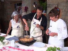 three people in aprons are cooking food on a table