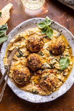 a bowl filled with pasta and meatballs on top of a table next to a spoon