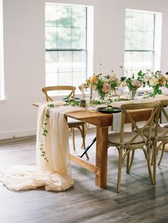 the table is set with white flowers and greenery for an elegant wedding reception at home