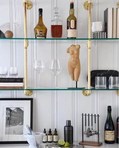 shelves with bottles and glasses on them in front of a wall mounted wine rack filled with liquor