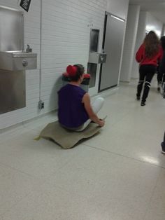 a woman sitting on the floor in front of a wall holding a white toilet bowl