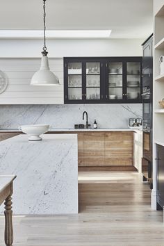 a kitchen with marble counter tops and wooden cabinets, along with an island in the middle