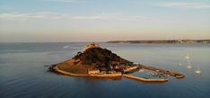 an island in the middle of water with boats on it and a castle like structure at the top