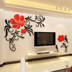 a living room with white walls and red flowers on the wall, in front of a flat screen tv