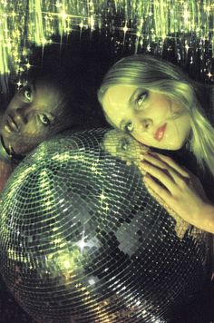 two people standing next to each other in front of a disco ball