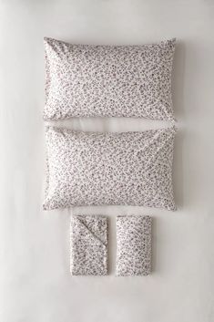 three pillows and two pillow cases on top of each other, one with a flower pattern