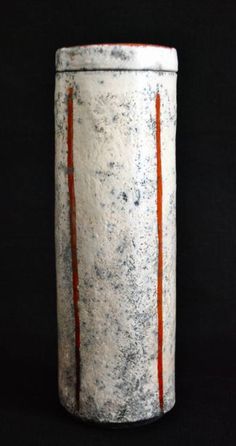 a white and orange vase sitting on top of a black surface