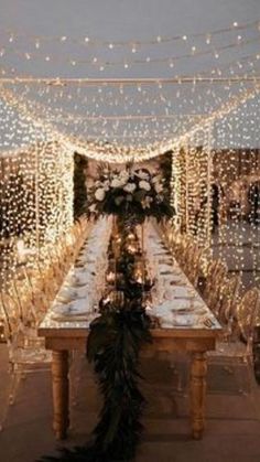 a long table with lights strung over it and some feathers on the table in front of it
