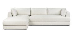 a white sectional couch with pillows on the back and foot rest in front of it