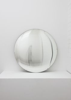 a round mirror sitting on top of a white shelf