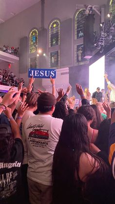 a group of people standing in front of a crowd holding up signs that say jesus