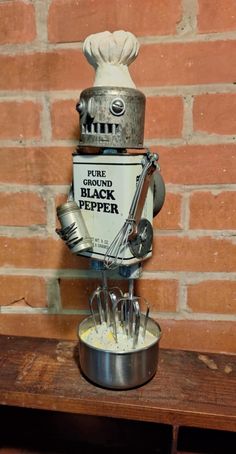 an old fashioned blender sitting on top of a wooden table next to a brick wall