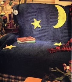 a crocheted blanket with stars and moon on it sitting on a couch in a living room