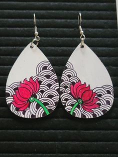 a pair of white and red earrings with flowers painted on the side of each tear