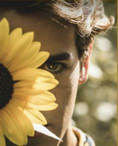 a man holding a sunflower up to his face