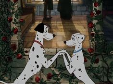 two dalmatian dogs playing with each other in front of roses and an archway