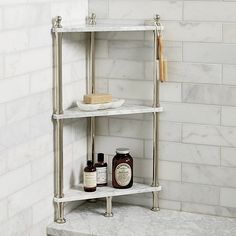 a bathroom shelf with bottles and soaps on it in front of a white tiled wall