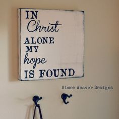 a sign that says in christ alone my hope is found above two hooks on the wall