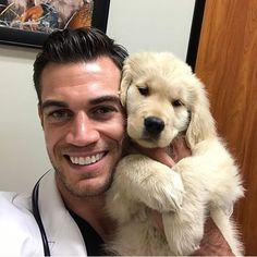 a man holding a white dog in his arms with a stethoscope next to him