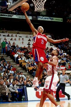 a basketball player jumping up to dunk the ball in front of an audience at a game