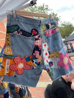 a pair of jean shorts with patchwork and flowers on them hanging from a clothes line
