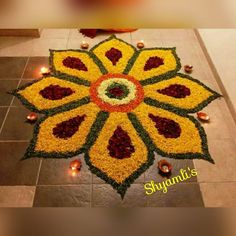 a decorated floor with candles and flowers in the shape of a flower on top of it