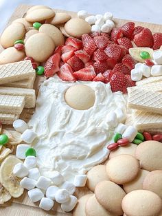 a wooden board topped with lots of different types of cookies and marshmallows