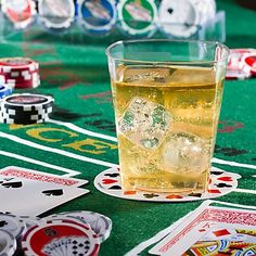 a glass of ice tea sitting on top of a table next to playing cards and chips