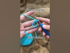 someone is knitting something with blue yarn on the end of a pair of crochet hooks