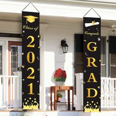 two black and gold graduation banners on the front porch of a house with red flowers