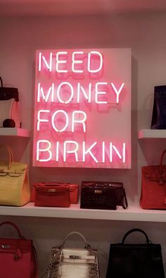 a pink neon sign that says need money for birkinn in front of purses and handbags
