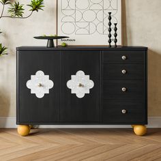 a black cabinet with two white flowers on the front and one yellow flower on the back