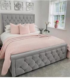 a bed with pink sheets and pillows in a room