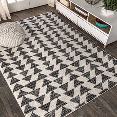 a black and white area rug on the floor in front of a cabinet with drawers