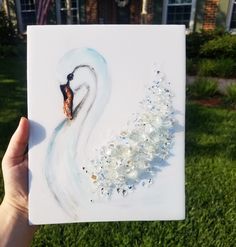 a hand holding up a piece of art that looks like a swan